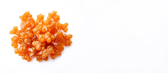 Close-up texture of orange and yellow multivitamin gummies in the form of bears on white background. 