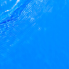 Obraz premium Surface of blue swimming pool water with light reflection. Texture of transparent blue water with ripples and waves in swimming pool. Trendy abstract nature background.