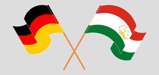 Crossed and waving flags of Germany and Tajikistan