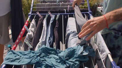 The man's hands hang wet clothes on the dryer. They make even lines to dry the fabric. Fresh linen.