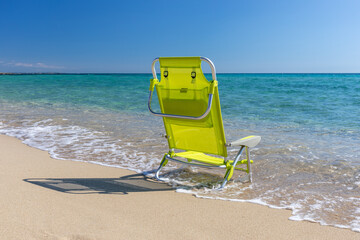 View of a chaise lounge on the beach with transparent water