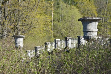 A bridge with ancient bowls through the spring foliage. Russia, Pavlovsk 