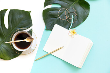 Tropical workspace concept. Notepad and tropical palm leaves. Mockup presentation workplace.