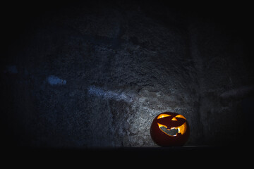 halloween abobora com cara luminosa e sorridente no com parede de pedra no fundo