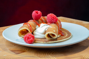 A plate of fluffy Norwegian pancakes with caramelized whipped cream and raspberry jam on the side.