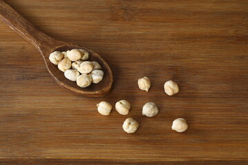 Fototapeta na wymiar Dry chickpeas in a wooden spoon close-up on a wooden background. Vegetarian food.