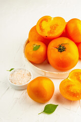 Ripe orange tomatoes with fresh basil. New harvest vegetables on a ceramic stand