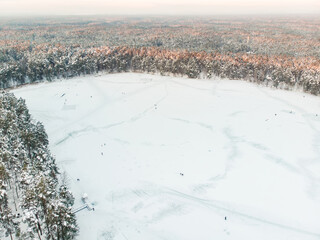 Beautiful aerial view of ice covered Balzis lake. Snowy pine forests surrounding a small lake. Rime ice and hoar frost covering trees. Winter landscape near Vilnius, Lithuania.