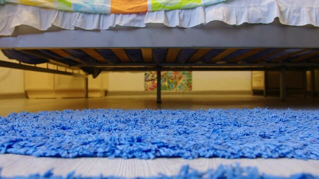 Faceless girl woke up, sat on bed, put on pink slippers, got up and went. Female slender legs slip down from bedstead, provide with warm, soft house shoes in morning. Bottom view. Cozy room