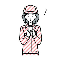 立ってスマートフォンを操作して何かに気づいて驚いた作業員の女性