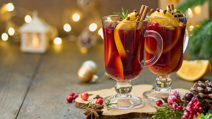 Two glasses of hot red mulled wine beverages with cardamom, cinnamon, clove, orange, anise,...
