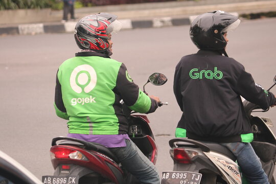 March 09, 2020, Sleman, Indonesia: Gojek Driver wearing Jacket with Gojek Logo side by side with grab driver. Gojek is Indonesian transportation startup.