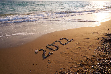 2022 Happy new year concept. Top view of 2022 numbers written on the sand of coastline with wave.Message hand written in golden sand on beautiful sunset or sunrise golden sky background            