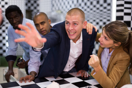 Focused Man Pointing To Something While Trying To Find Solution Of Conundrum With Friends In Quest Room