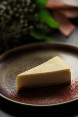 Classic white cheesecake in a clay plate on the background of a bouquet of flowers.