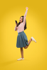 portrait of attractive woman raising one hand and leg while using a smartphone