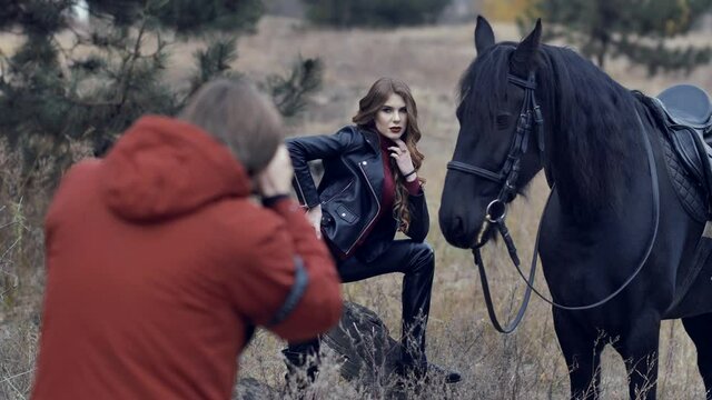 Beautiful young woman with horse posing for photographer at outdoor photo shoot