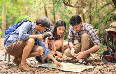 A group of young Asians are planning and looking at maps for camping in the forest.Asian and...