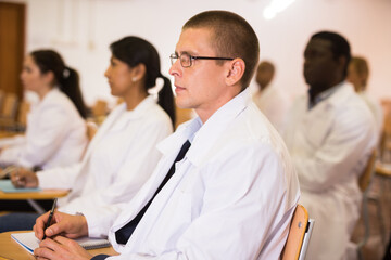 Fototapeta premium Portrait of confident man doctor listening to lecture within refresher course. Professional development concept