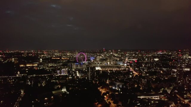 Aerial panoramic footage of large city at night. Illuminated landmarks, street lights and traffic from height. London, UK