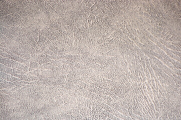 Obraz premium Fragment of light gray natural leather with wrinkles and white folds close-up.