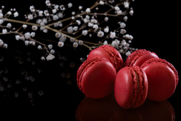Red French Macarons with Flowers on Black Background.