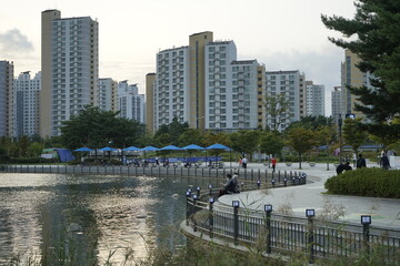 김포호수공원에는 고층아파트와 산책하는 사람들과 휴식하는 사람들이 있습니다.
