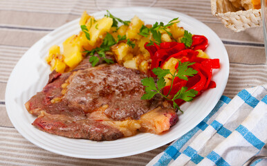 Appetizing beef entrecote with french fries and stewed bell peppers served at plate