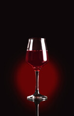 Glass of delicious red wine on black background