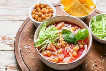Tasty pozole soup in bowl and ingredients on light wooden background, closeup