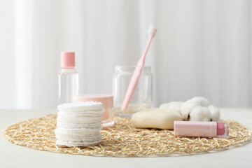 Wicker mat with clean cotton pads and cosmetics on light table