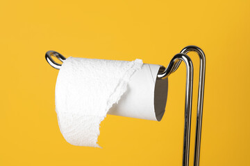 Holder with cardboard tube for toilet paper on orange background, closeup