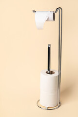 Modern holder with cardboard tube and toilet paper rolls on beige background
