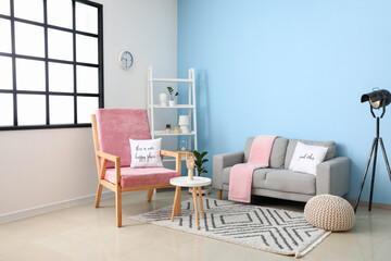 Interior of stylish room with comfortable armchair and sofa near color wall