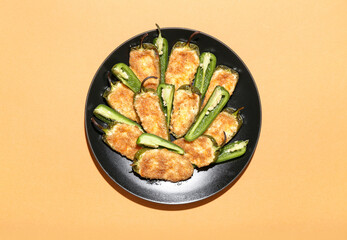 Plate with delicious jalapeno poppers on color background
