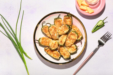 Plate with tasty jalapeno poppers on light background