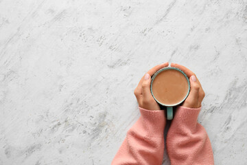 Female hands with cup of hot cacao on light background