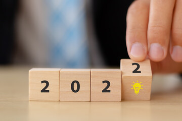 Business development concept in 2022 for new ideas creativity and innovative solution. Wooden cubes with "2022" and  light bulb symbol on the smart background and copy space. Used for banner.