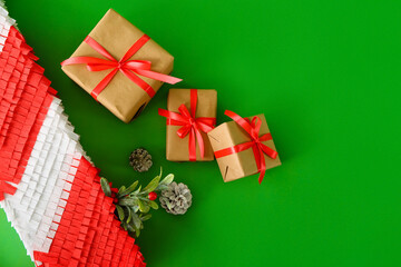 Mexican pinata with pine cones and gifts on green background