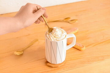 Female hand and cup of tasty Tiramisu Latte on wooden background