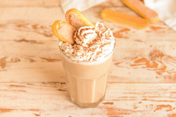 Glass of tasty Tiramisu Latte on white wooden background