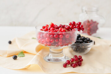 Bowl with tasty red currants on light background