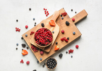 Bowl with tasty red currants and different berries on light background