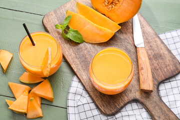 Glasses of tasty melon milkshake on color wooden background