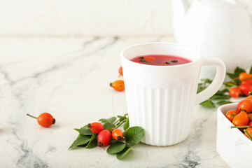 Obraz na płótnie Canvas Cup of tasty rose hip tea and berries on white marble background