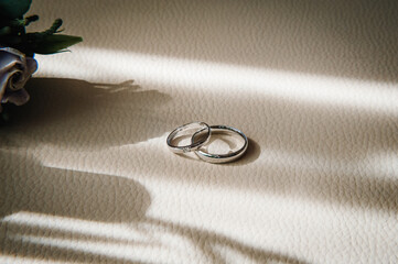 Designer Silver two wedding rings on a beige background with copy space. Engagement. Luxury marriage and wedding concept.