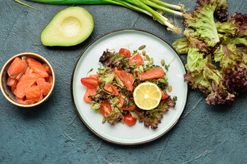 Tasty salad with salmon and vegetables in plate on dark background