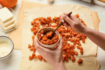 Woman cooking pumpkin strudel on light background