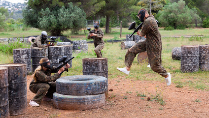 Fototapeta premium Group of people in full gear playing paintball on shooting range