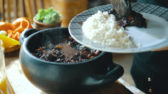 Serving feijoada, a Brazilian dish on a lunch table